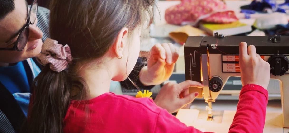 adult helping child sew