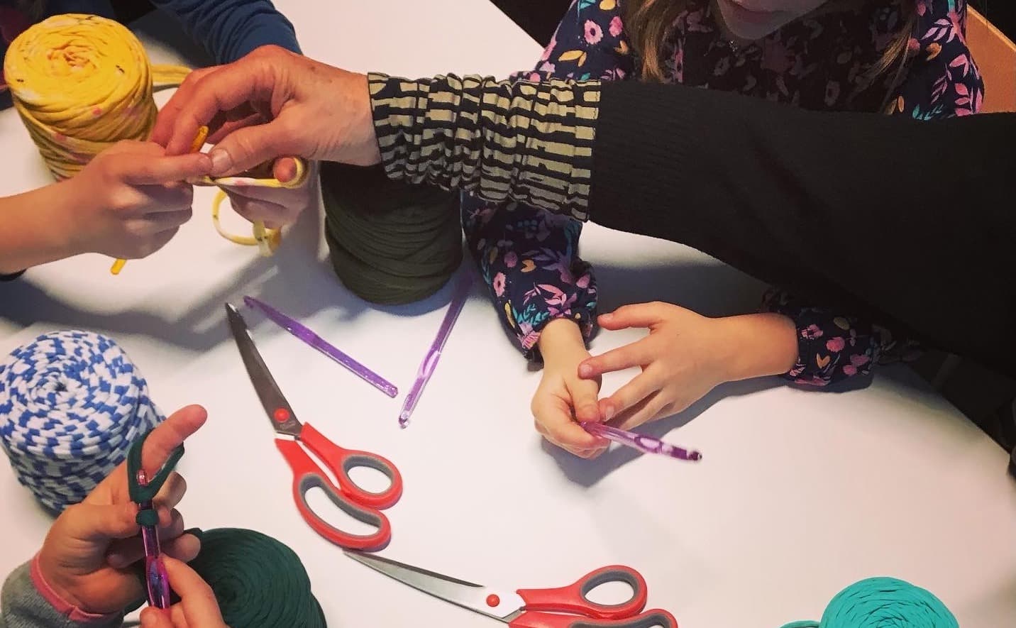 adult helping children crochet
