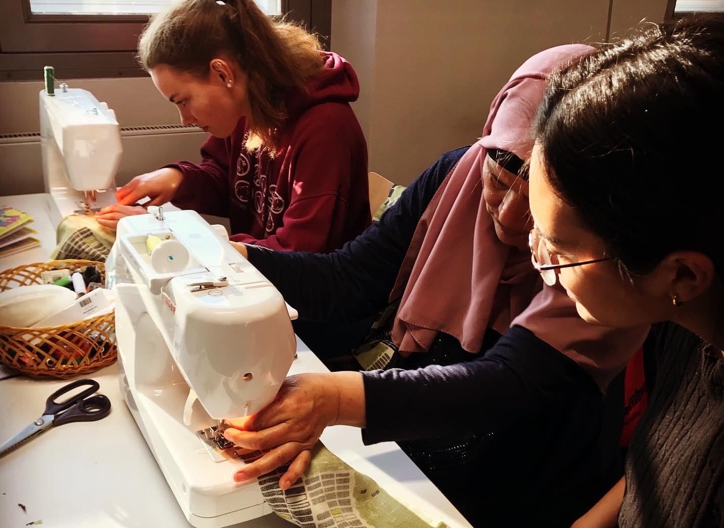 adult helping students sew